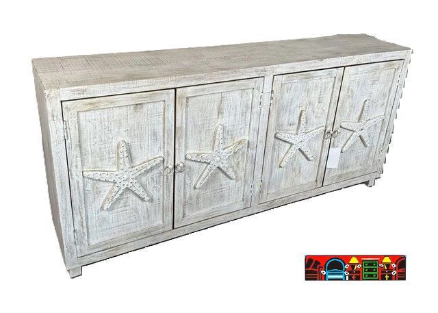A sideboard made of mango wood with a distressed white-wash finish. It has four doors, each adorned with a carved starfish. There is a shelf behind the doors for storage.