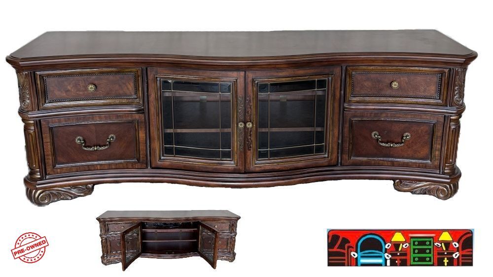 Entertainment console in dark brown, featuring a veneer top, four drawers, two glass-front doors, and a shelf, is available at Bratz-CFW in Fort Myers, FL.