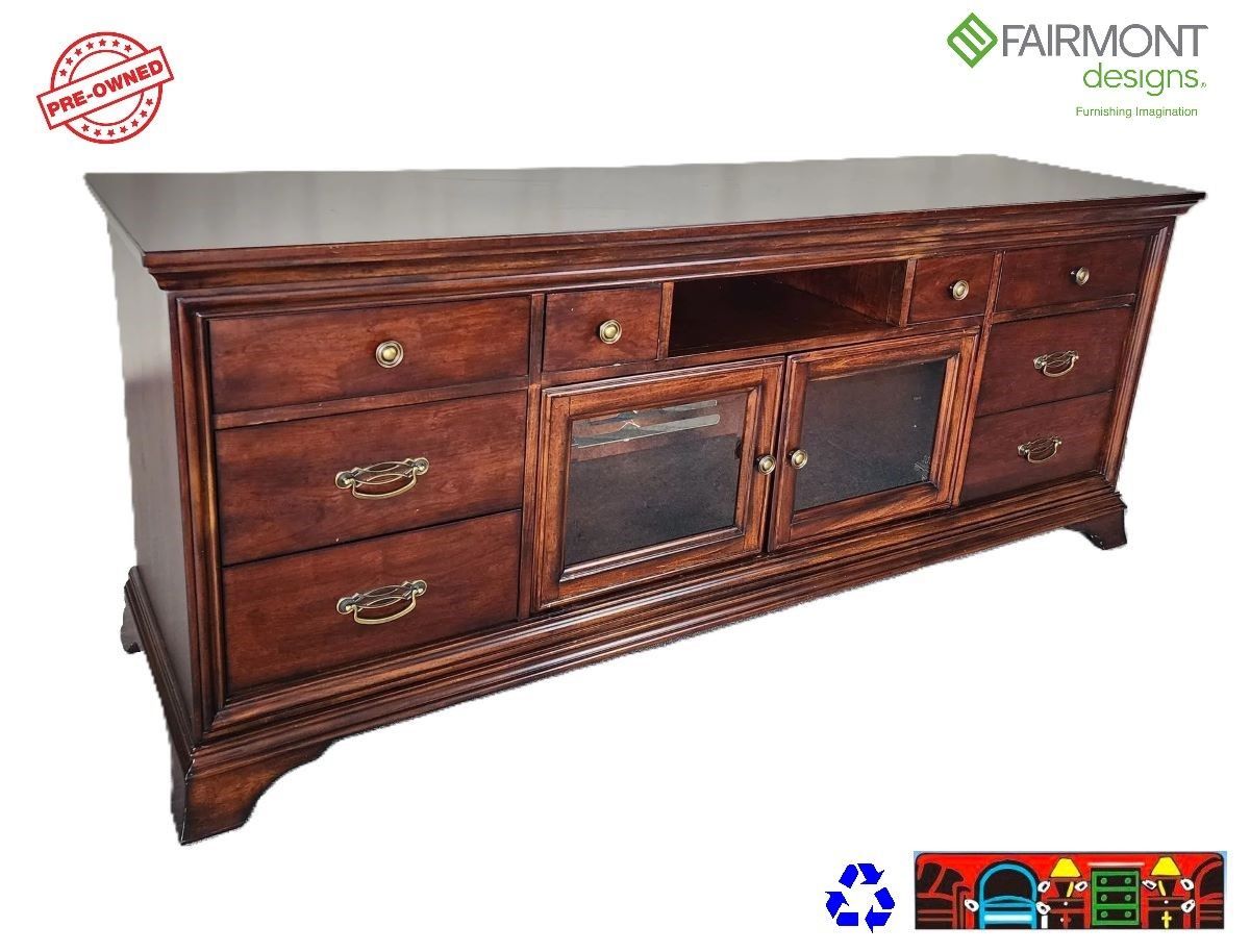 Dark wood entertainment console with 2 glass-front doors and drawers on either side and cubby in top center.