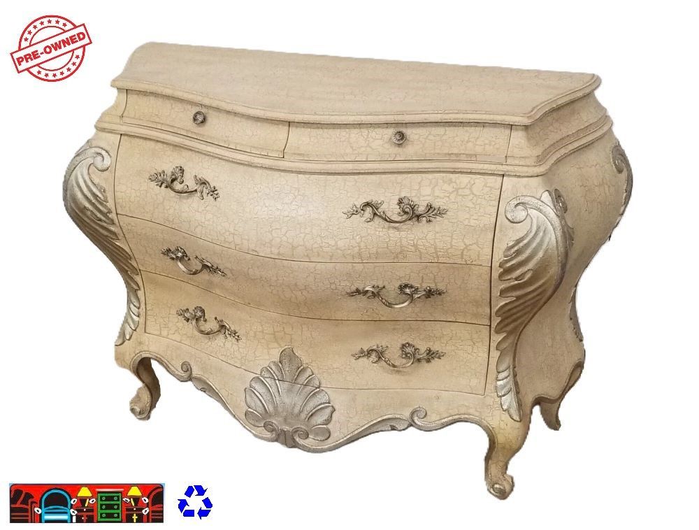 A large wooden Bombay chest with five drawers, featuring a cream crackle finish and silver carved accents, complete with iron handles, is available at Bratz-CFW in Fort Myers, FL.