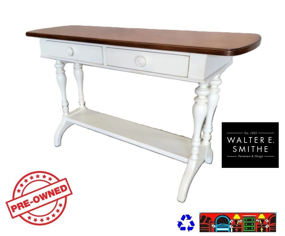 'Smith pre-owned Sofa Table: A two-toned piece featuring a white frame with a contrasting brown top. Equipped with two drawers, ornate central legs, and a convenient bottom shelf.'