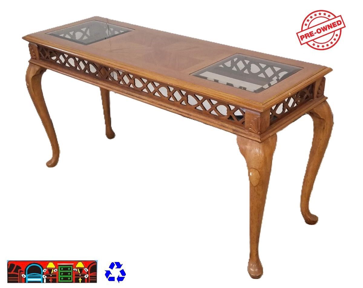 A sofa table made of natural wood, featuring dual glass inserts on the top and a lattice design on the sides.
