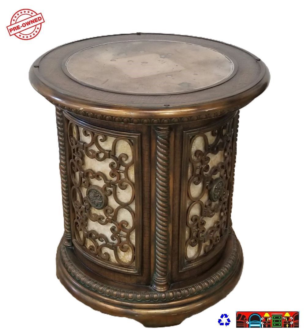 'A gently used vintage-style round end table crafted from solid wood, featuring an antiqued mirror at the center of the top, surrounded by iron and carved wood details set against a cream-colored background.'