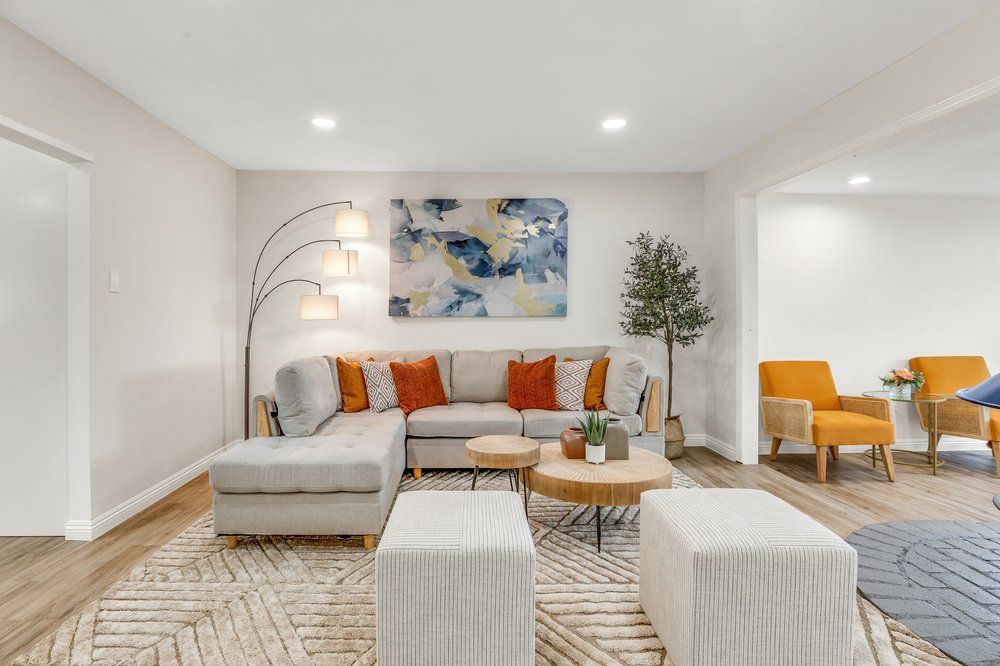 A living room with a couch , chairs , ottomans and a table.