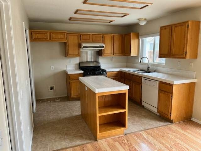 An empty kitchen with wooden cabinets and white counter tops