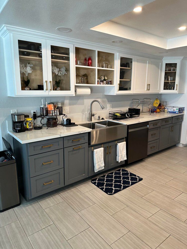 A kitchen with gray cabinets and a stainless steel sink.