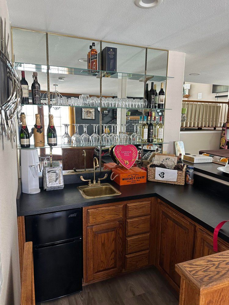 A kitchen with wooden cabinets , a sink , a refrigerator and a bar.