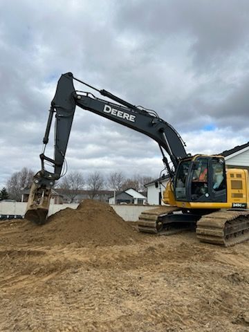 John Deere excavator with a pile of dirt, ready for backfill by a new house foundation