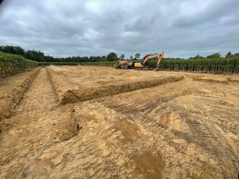 Excavator services. Barn preparation beside a field 