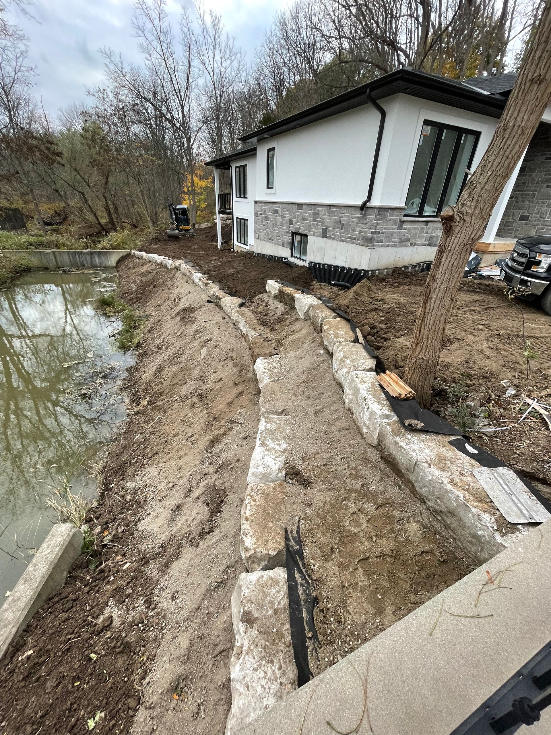 Completed stone wall/barrier to prevent house wash-out near a river.