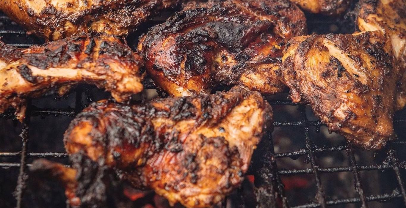 A close up of chicken wings cooking on a grill.