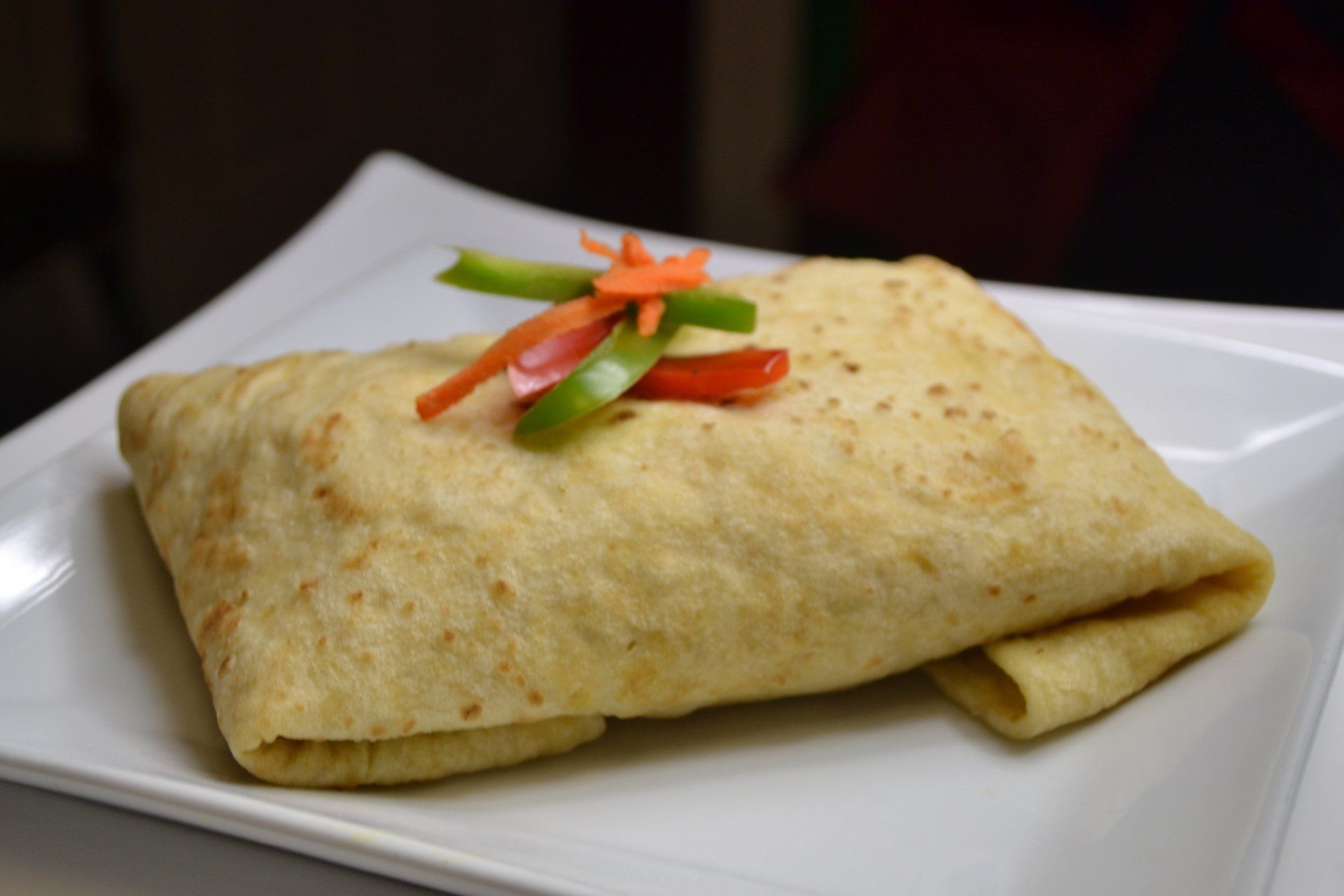 A white plate topped with a Roti  and vegetables