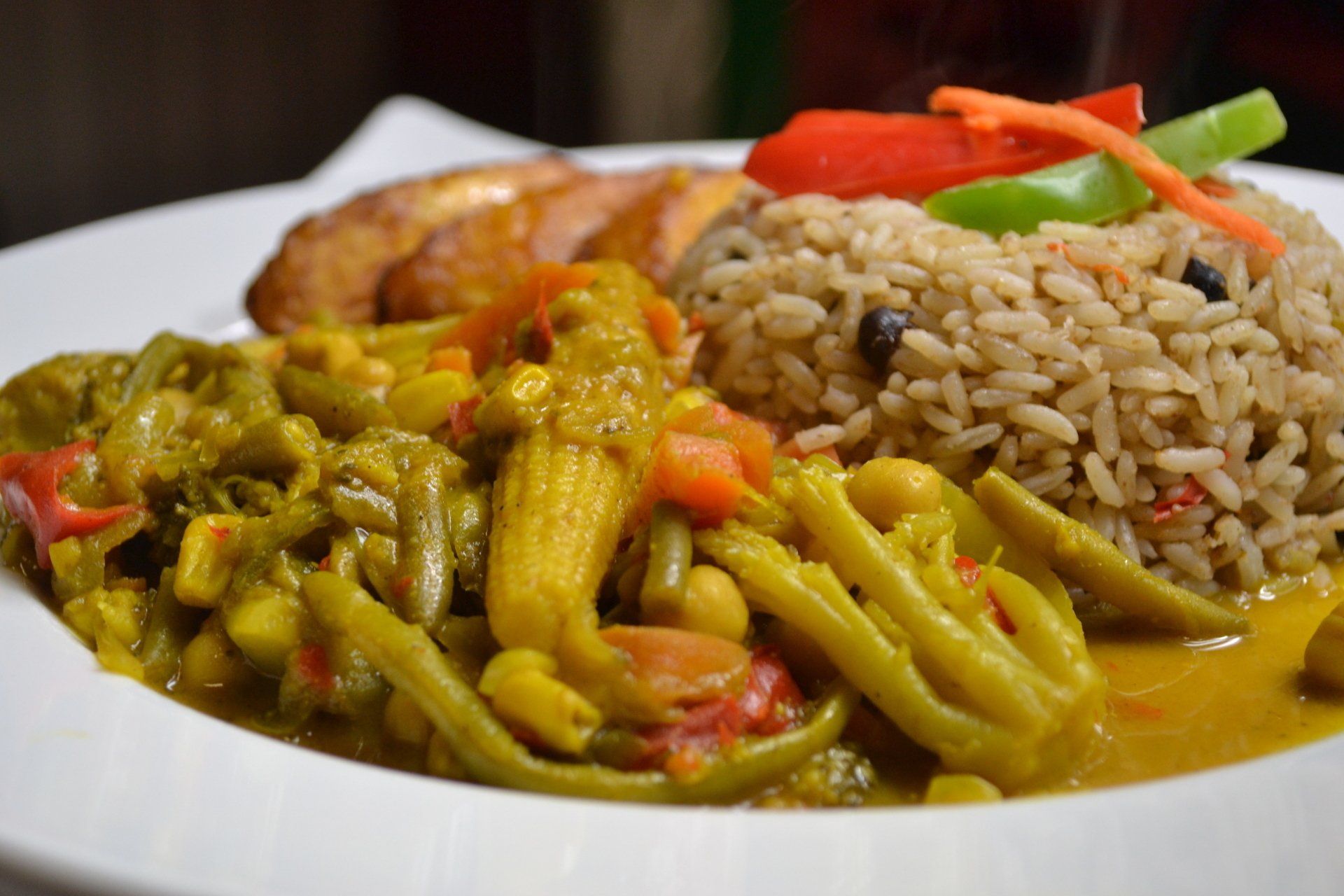 A close up of a plate of food with rice and vegetables on a table.