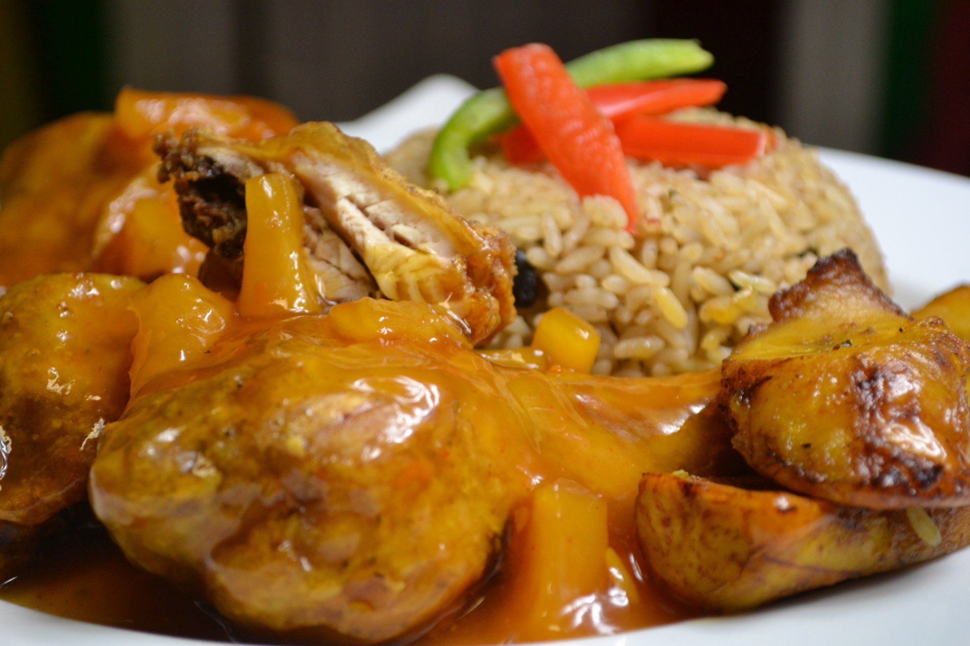 A close up of a plate of food with chicken and rice on a table.