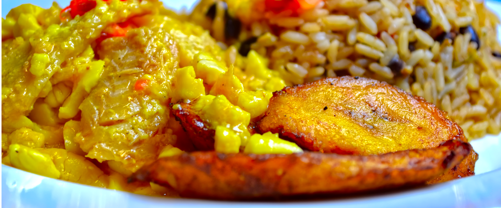 A close up of a plate of food with rice and plantains on a table.