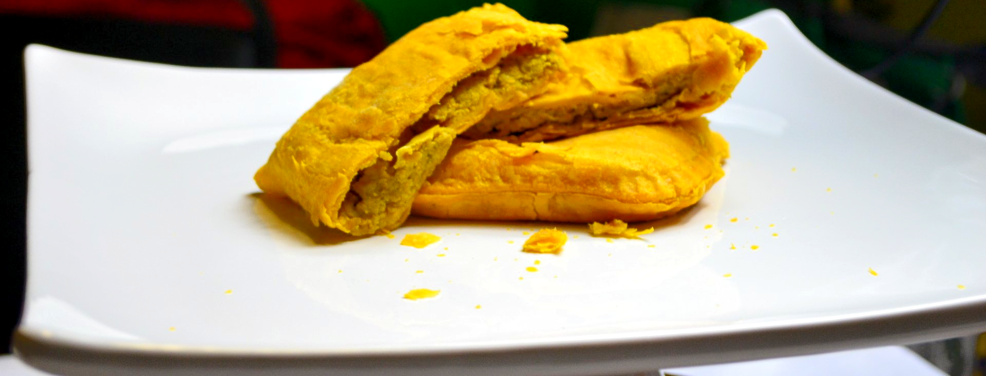 A close up of a Jamaican Patties on a white plate.