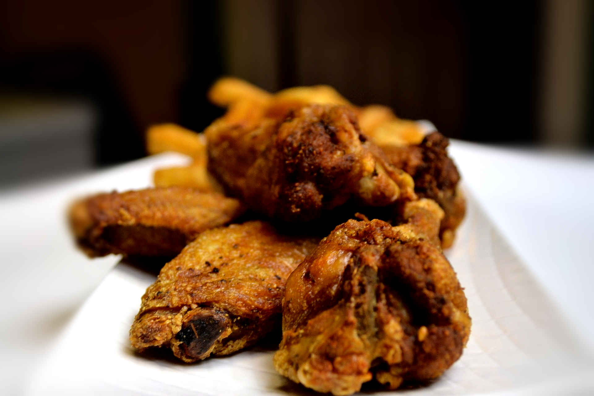 A white plate topped with fried chicken wings and french fries.