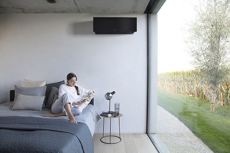 Uno showroom Daikin espone diverse unità di aria condizionata su uno sfondo blu, con un tavolo allestito in primo piano.