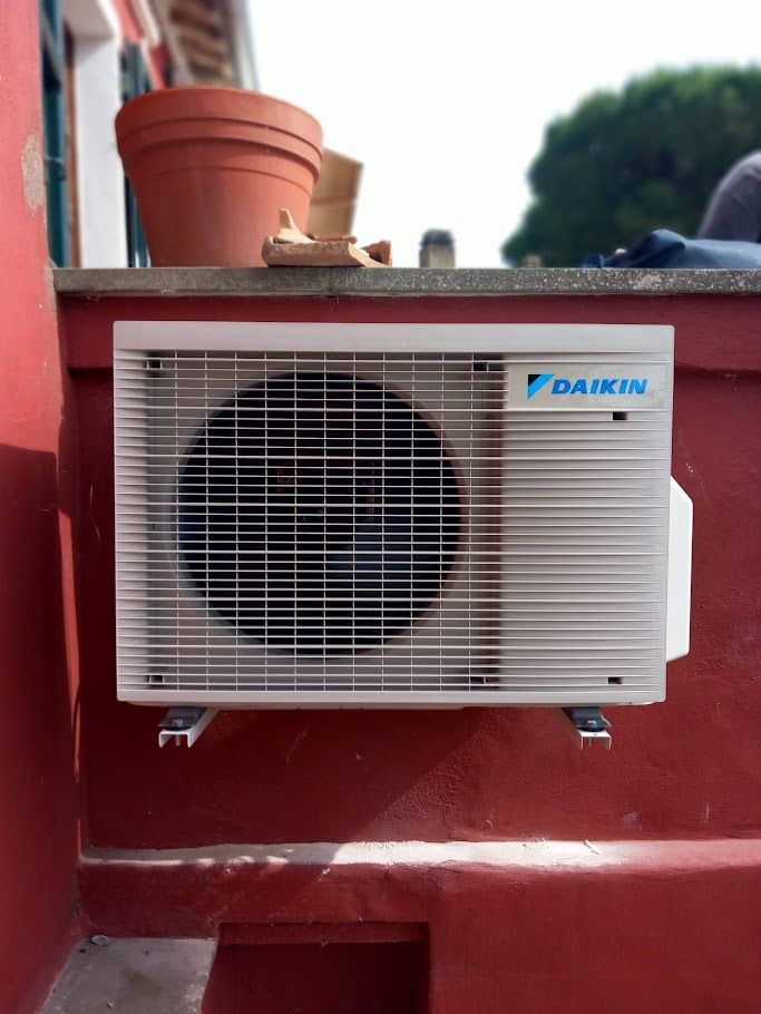 Condizionatore Daikin montato su una parete rossa, con una pentola sopra.