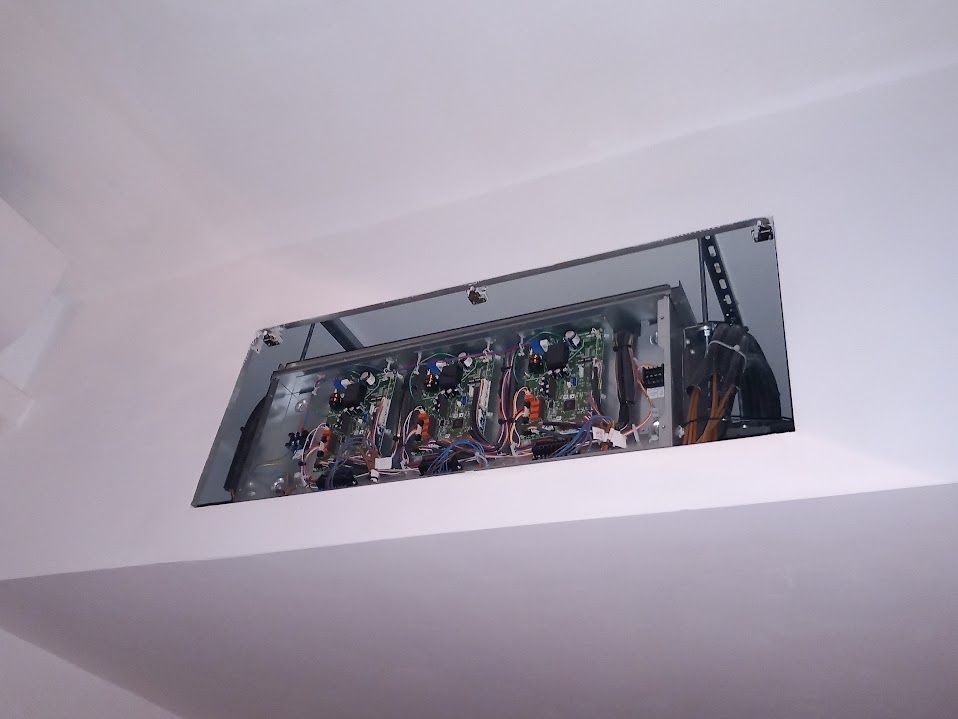 Un quadro elettrico aperto incassato in una parete bianca; fili e circuiti stampati visibili.