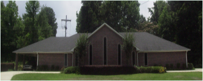 Red building with green trees behind it