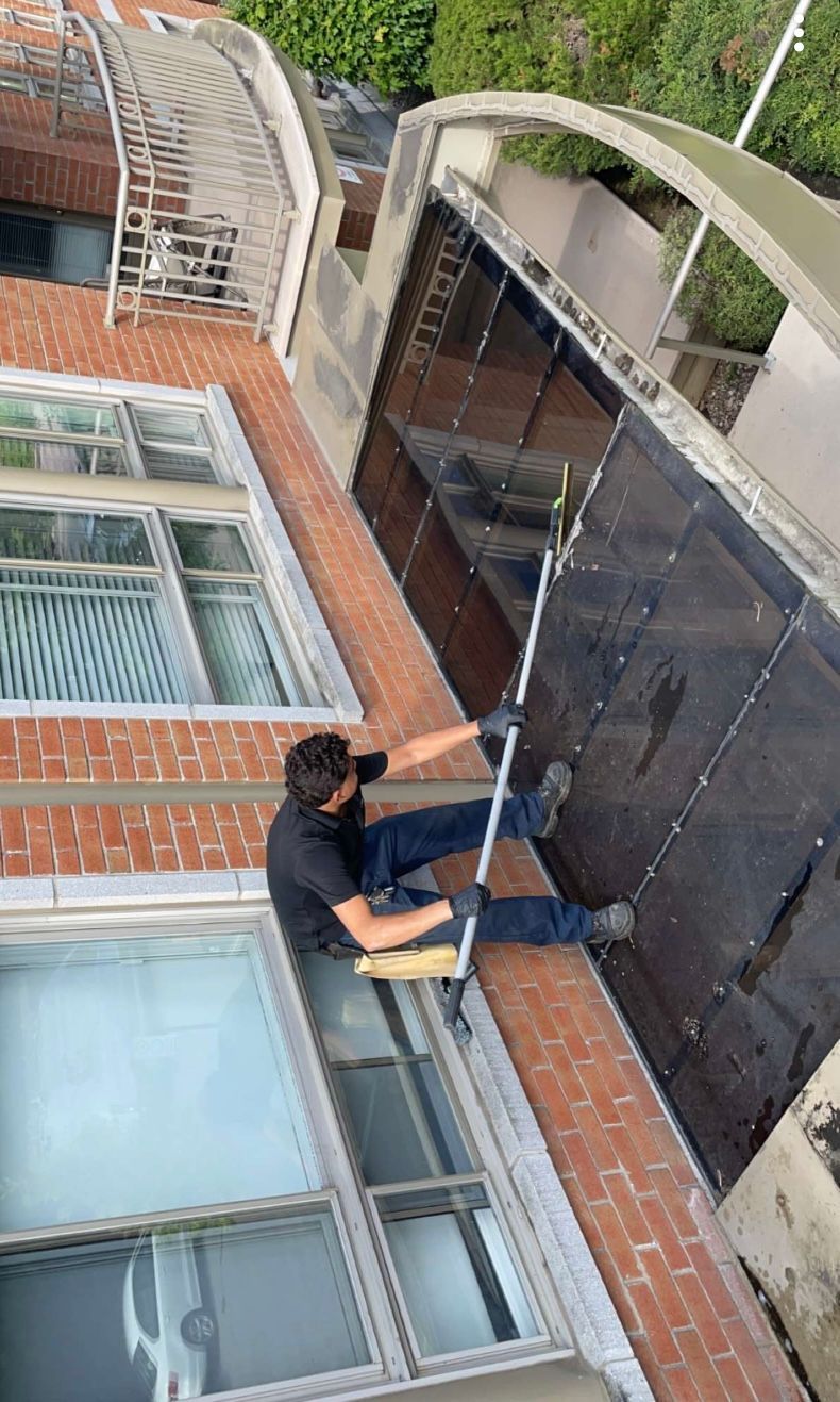 Un homme nettoie une fenêtre sur le côté d'un bâtiment.