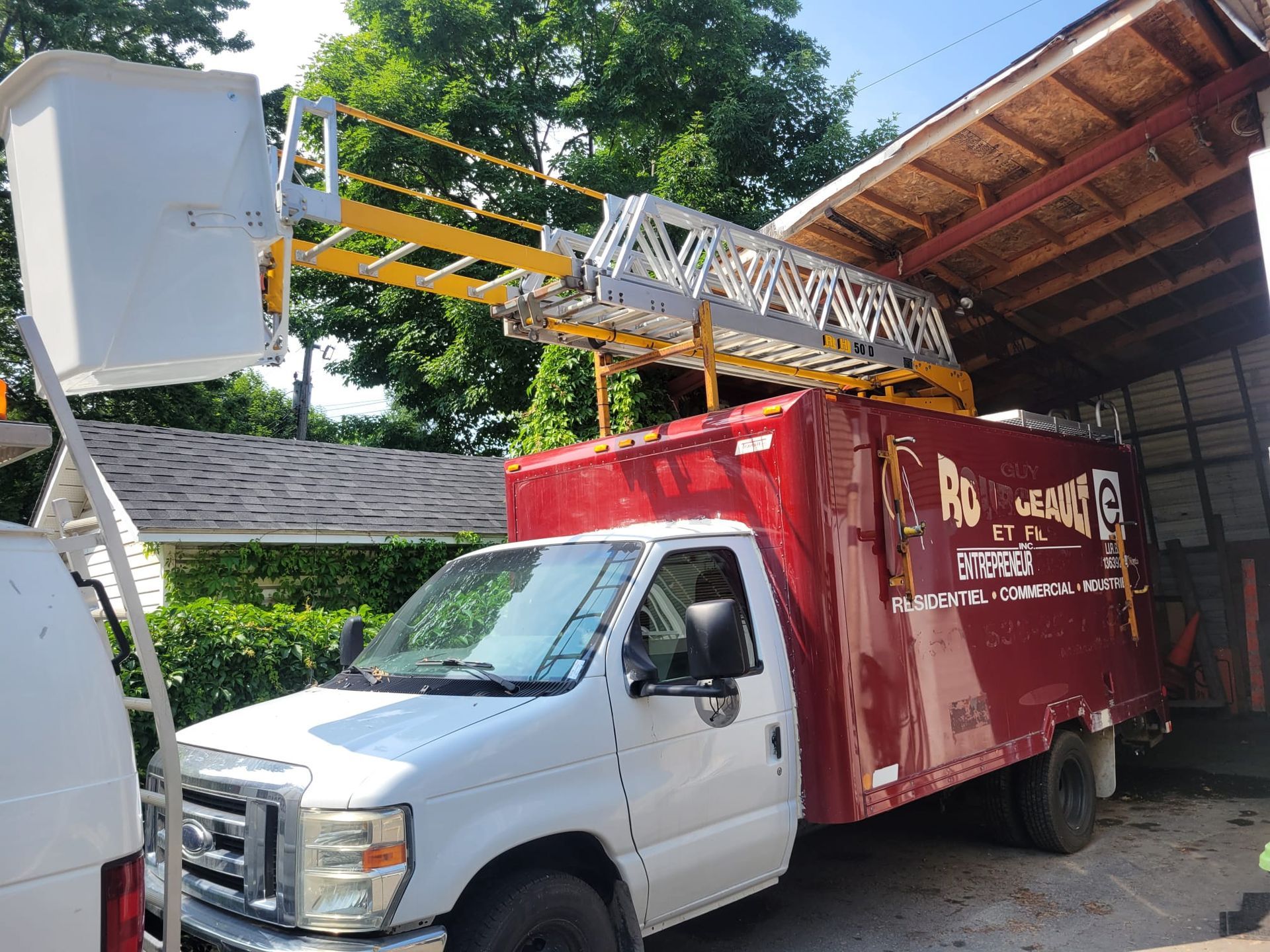 Un camion rouge et blanc avec une échelle dessus est garé devant un bâtiment.