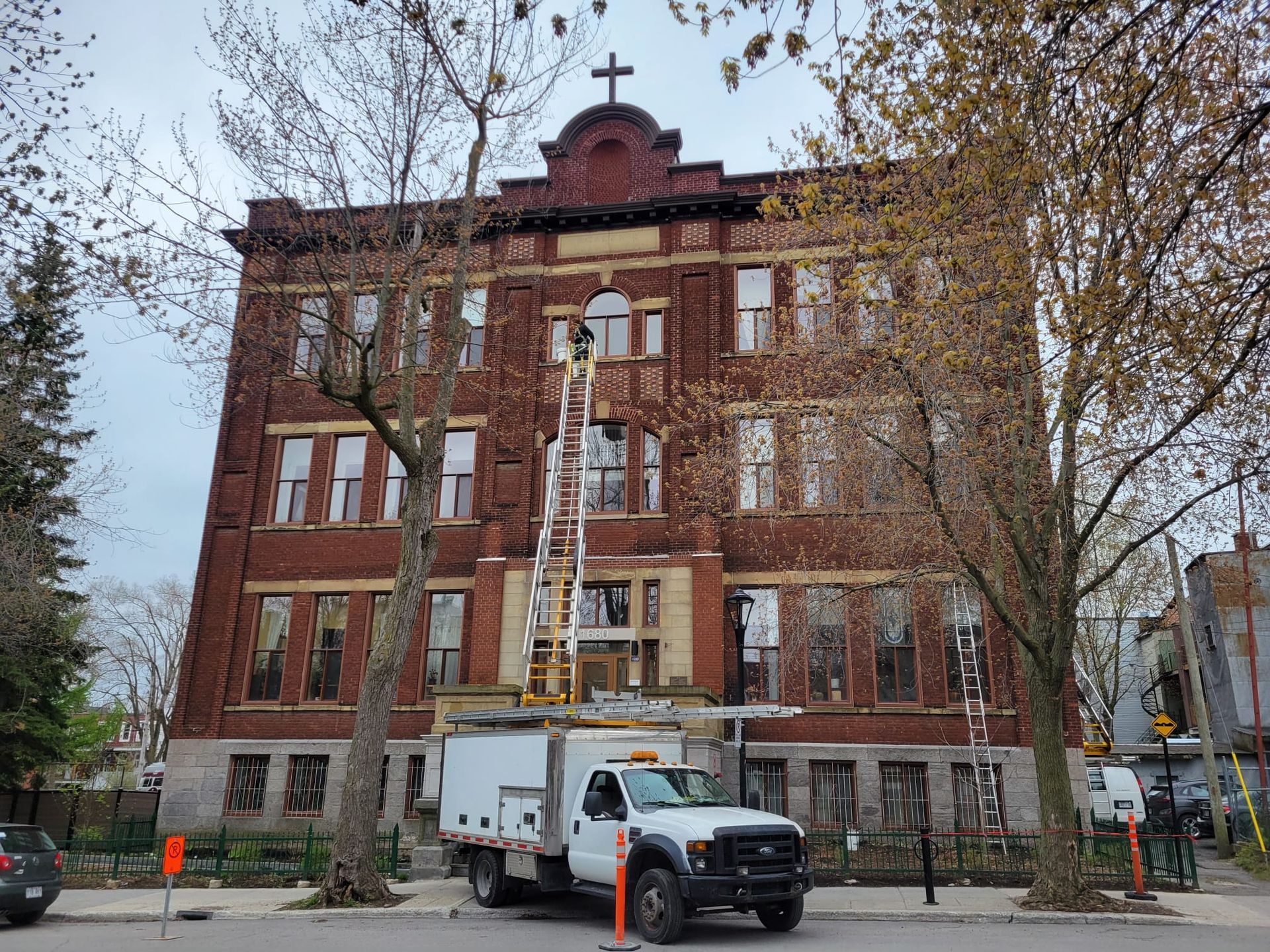 Un camion blanc est garé devant un grand bâtiment en briques.