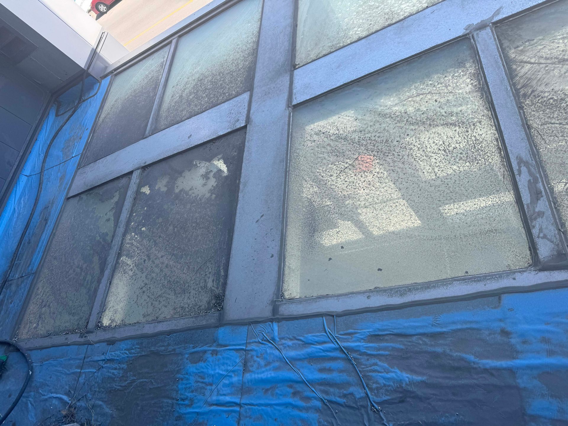 Une bâche bleue recouvre un bâtiment avec beaucoup de fenêtres.