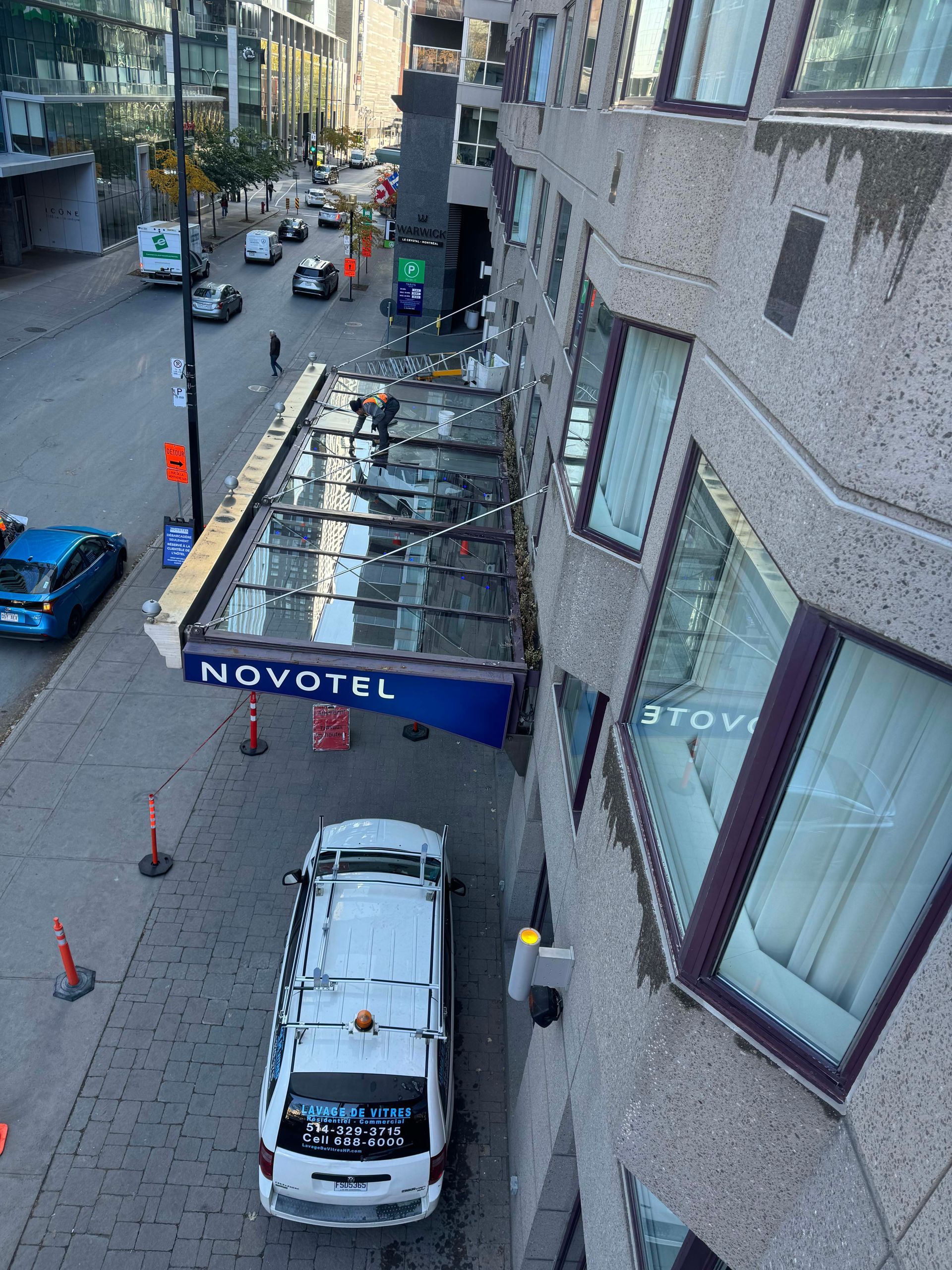 Une camionnette blanche est garée devant un hôtel Novotel