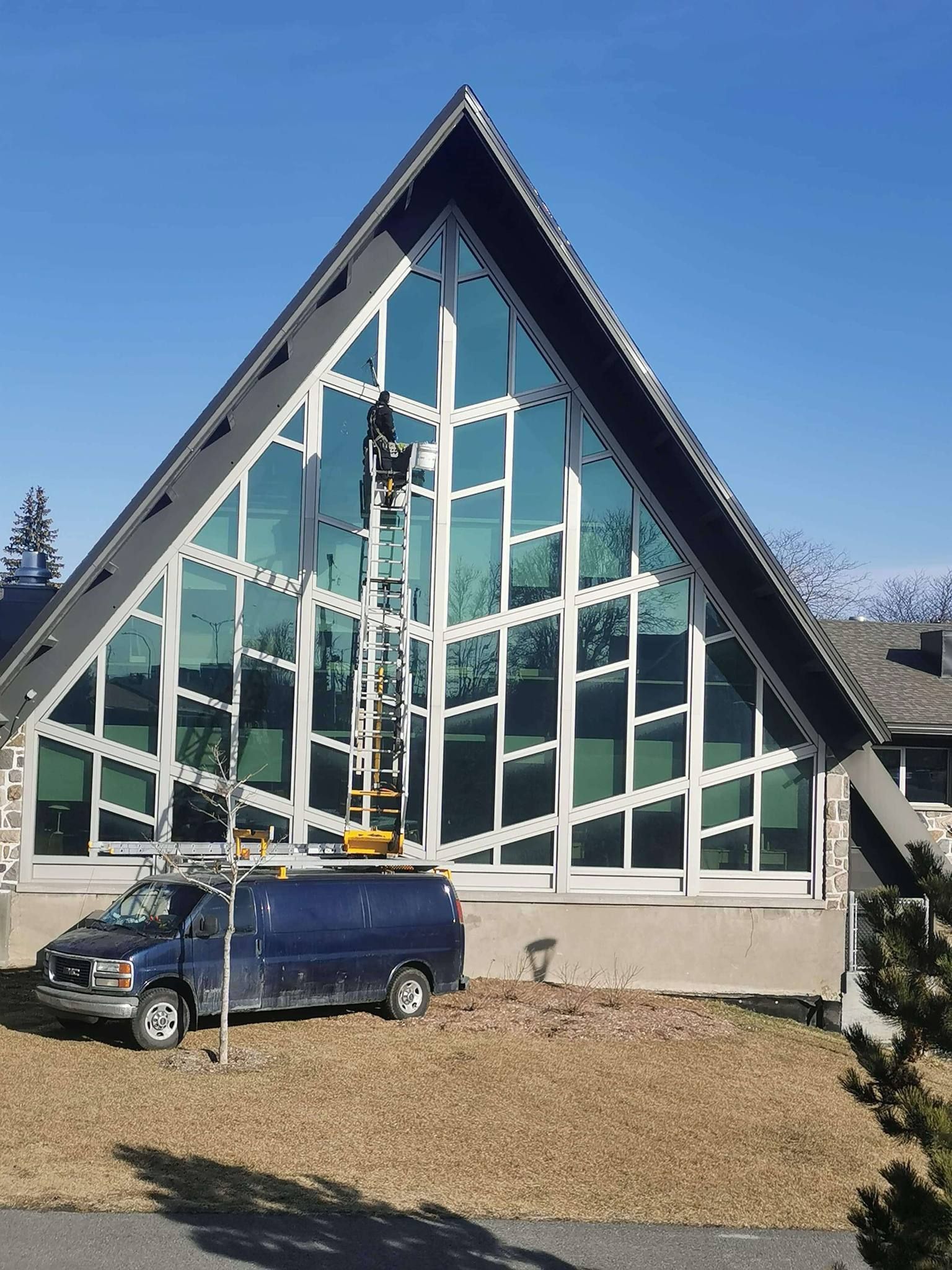 Une camionnette bleue est garée devant un grand bâtiment en forme de triangle.