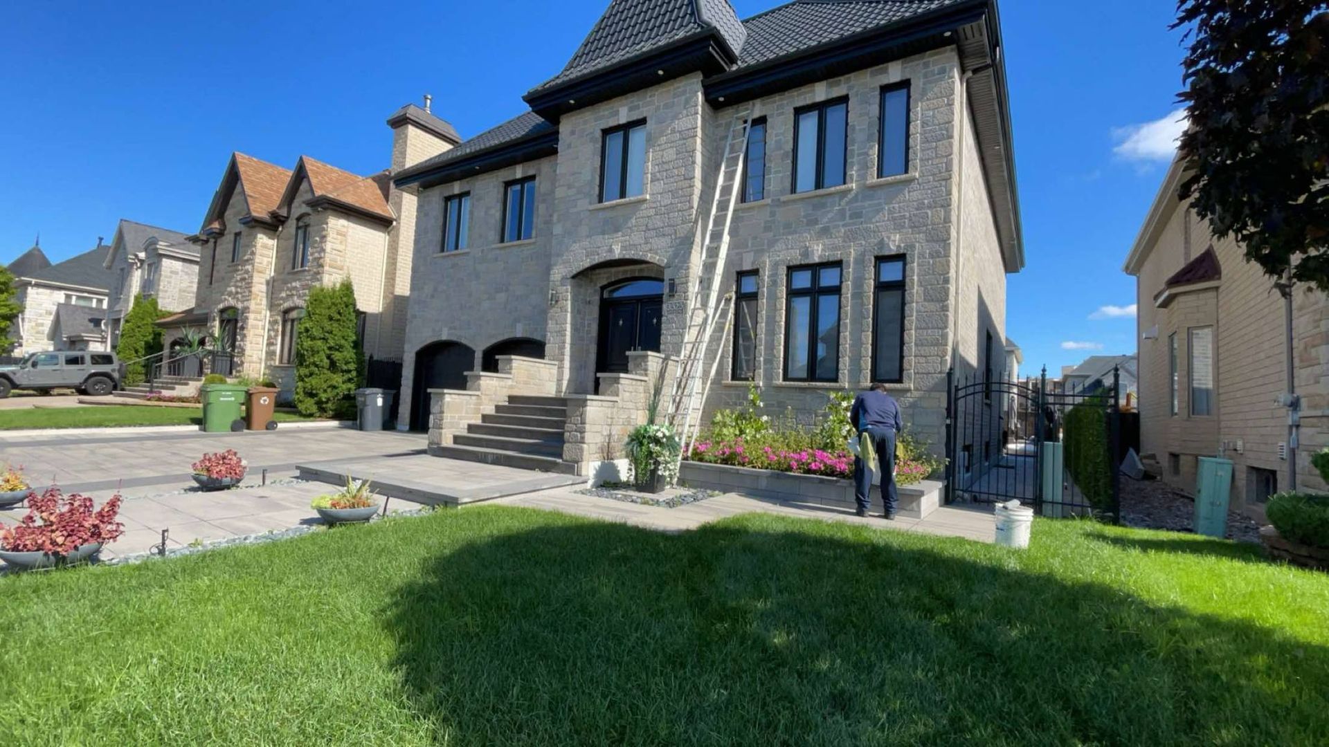Un homme se tient devant une grande maison en briques.