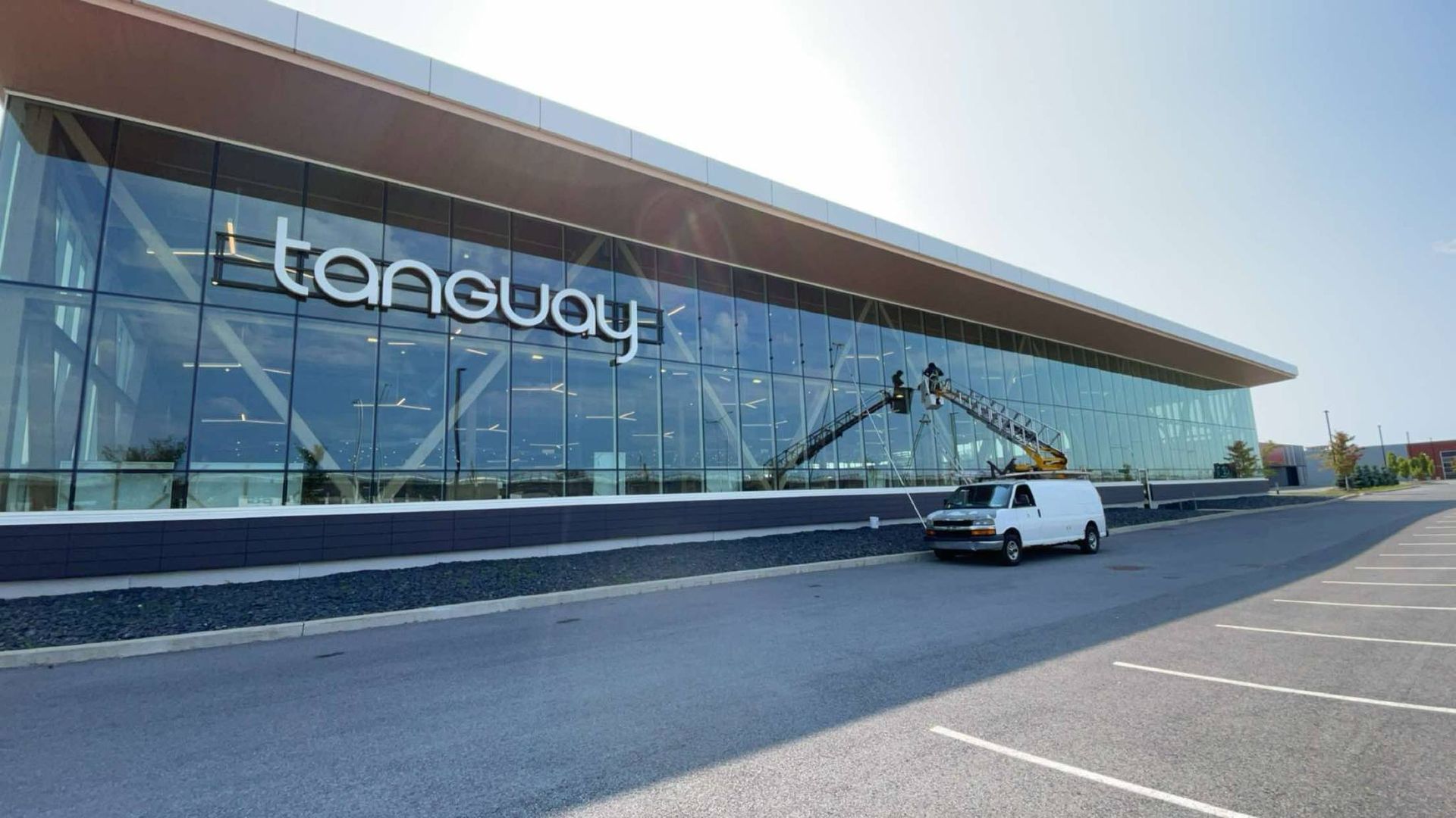 Une camionnette blanche est garée devant un grand bâtiment.