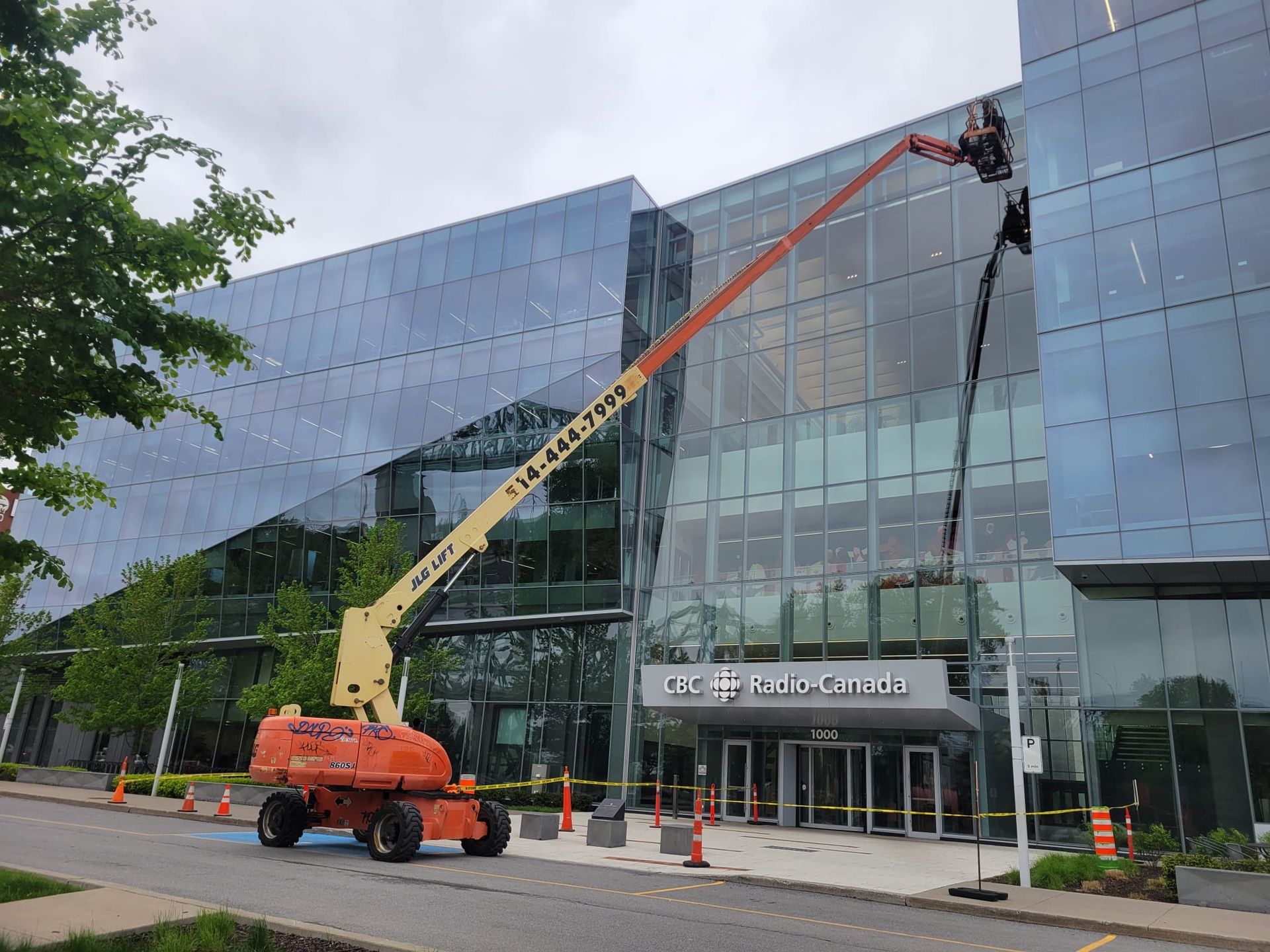 Une grue nettoie les fenêtres d'un grand bâtiment.
