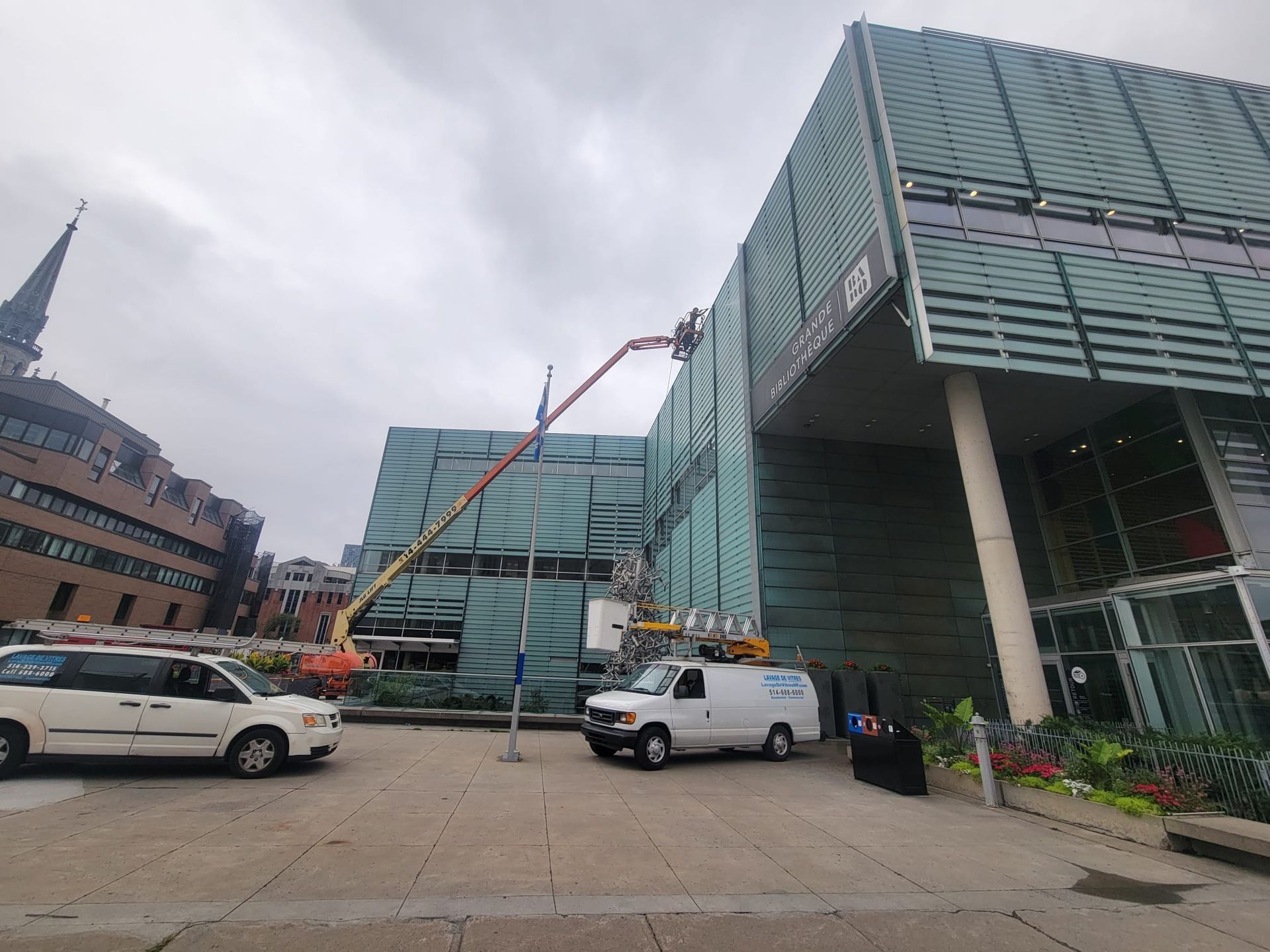 Une camionnette blanche est garée devant un grand bâtiment