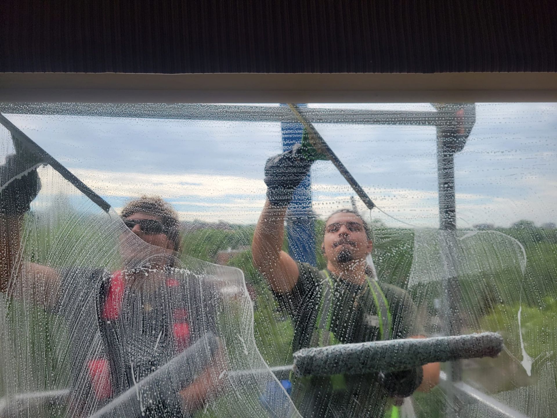 Un homme nettoie une fenêtre avec une raclette.