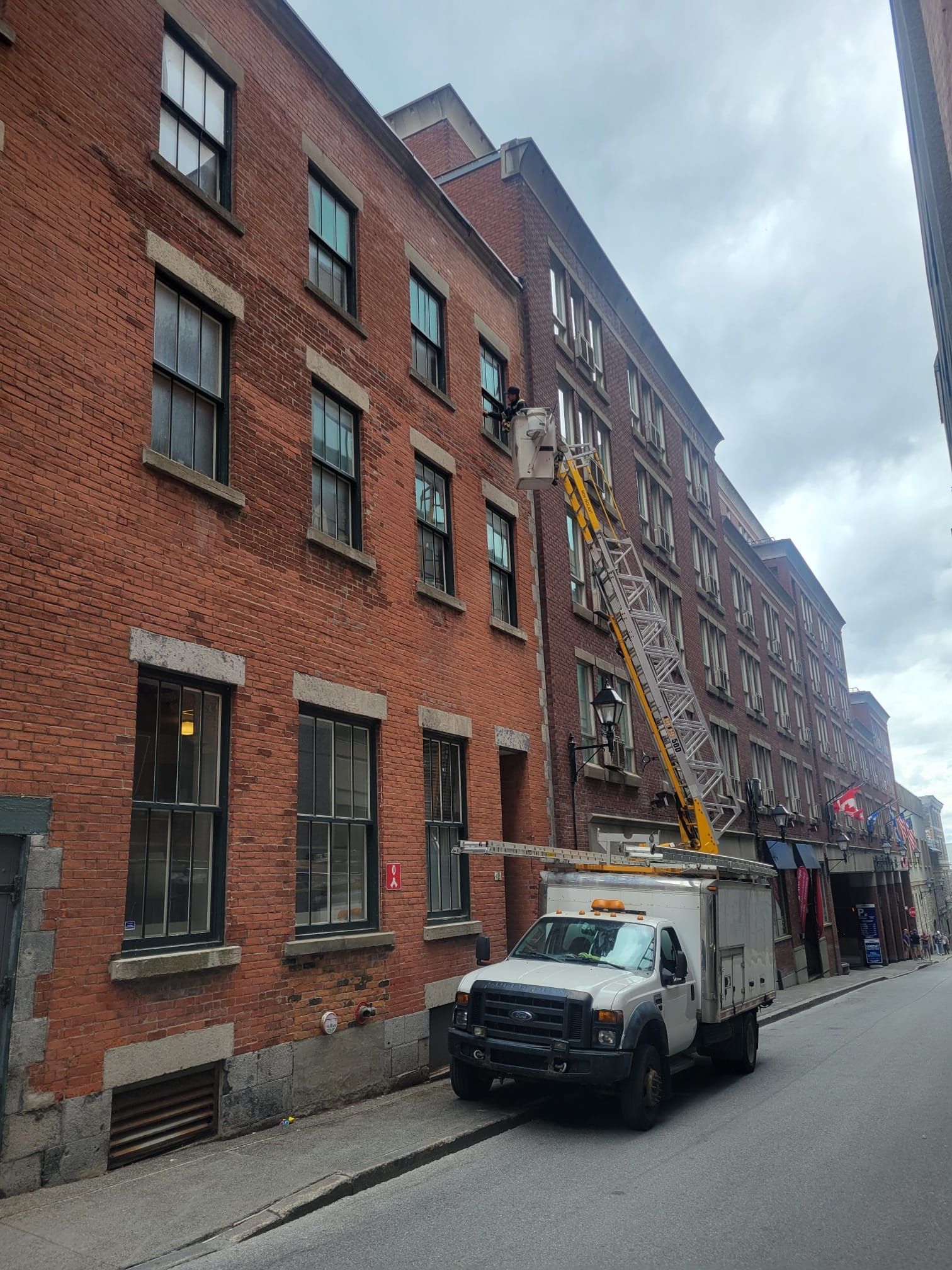 Un camion blanc est garé devant un grand bâtiment en briques.
