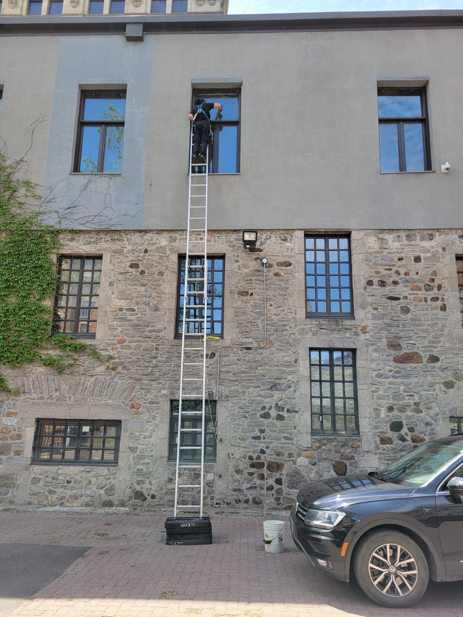 Un homme se tient sur une échelle sur le côté d'un bâtiment.