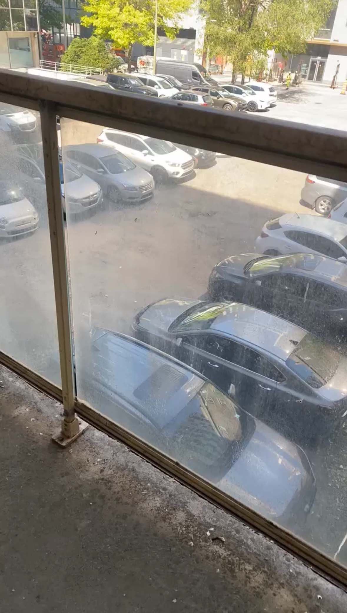 Un balcon avec vue sur un parking avec des voitures garées dedans.