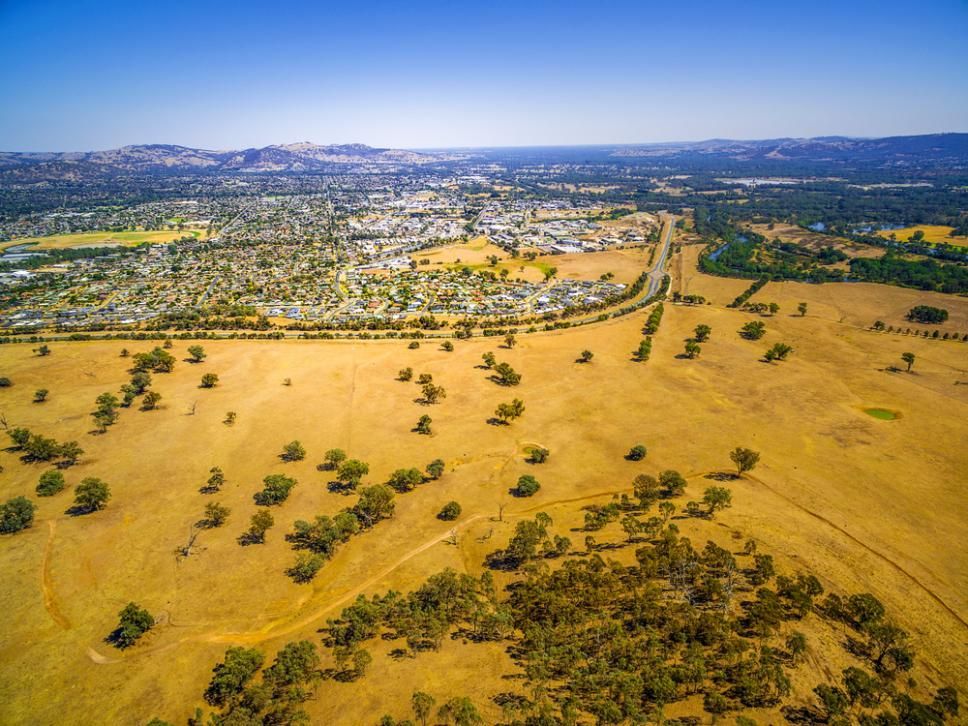 An Aerial View Of A Dry Grassy Field With Trees And A City — One Stop Bookkeeping in Goonellabah, NSW
