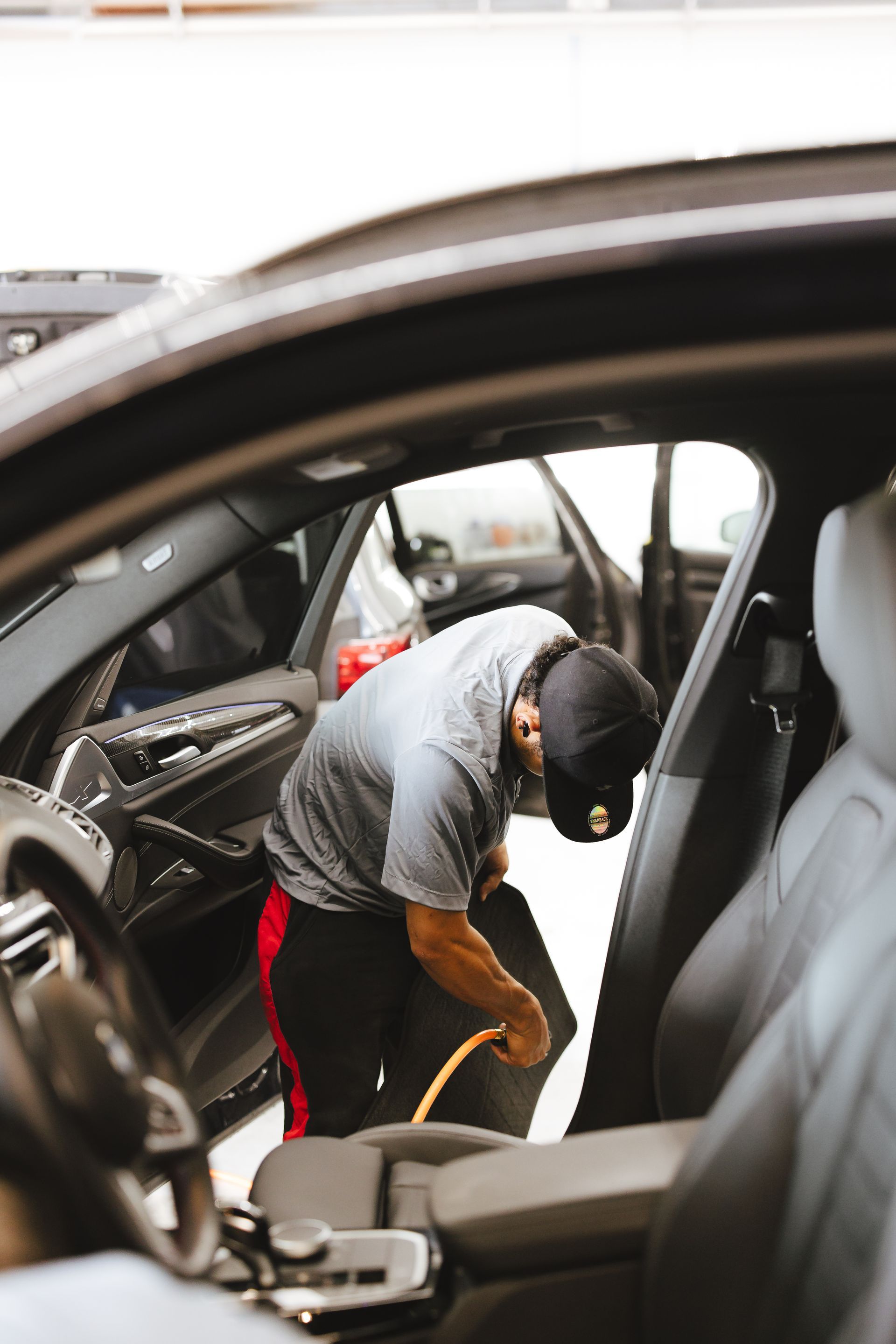A black mustang is parked in a parking lot with trees in the background.