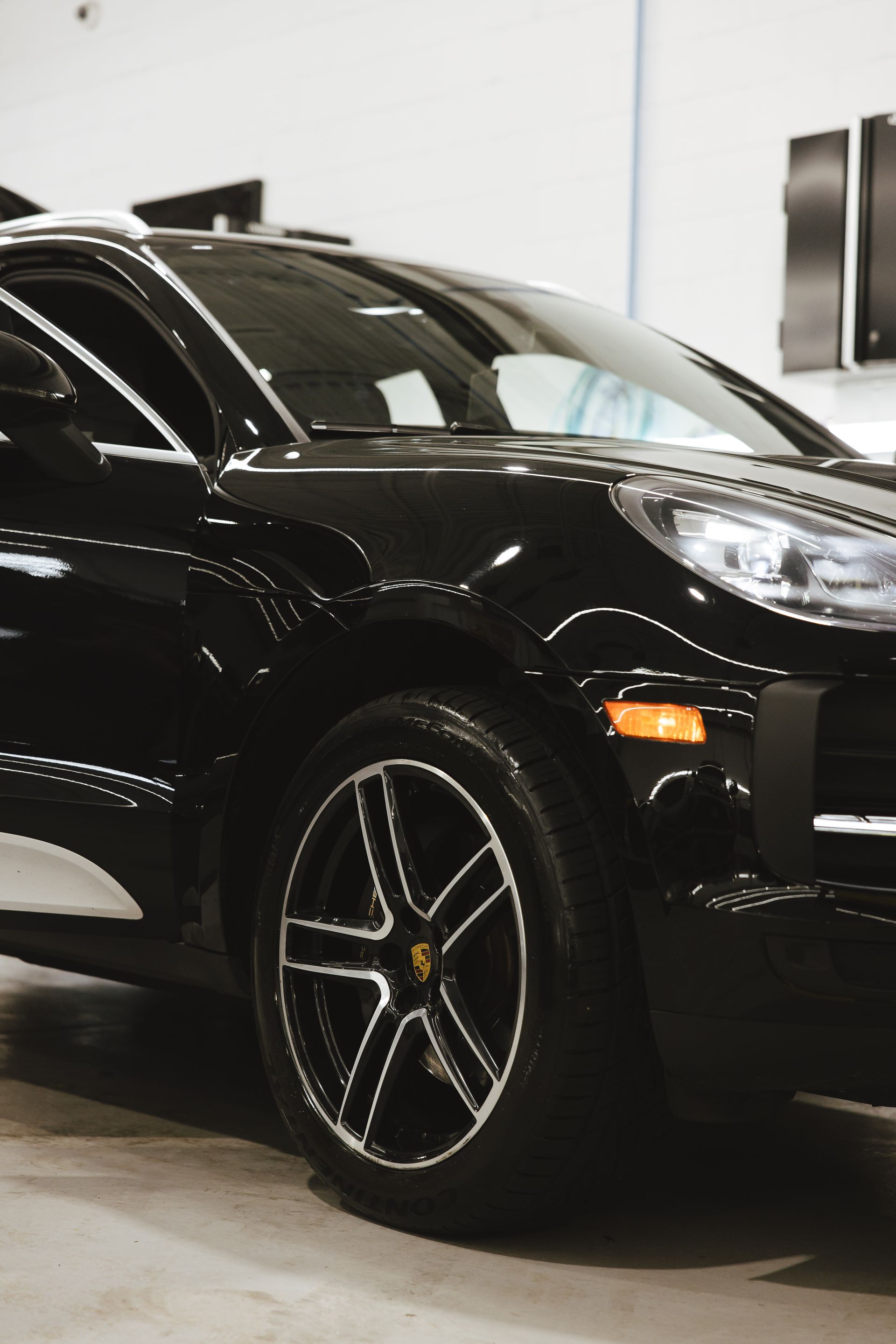 An orange car is parked under a bridge near the ocean.