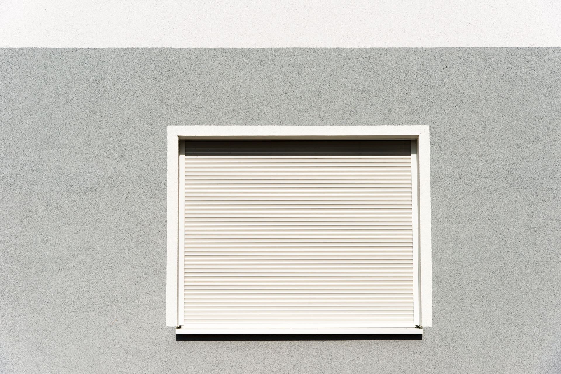 Una finestra con una persiana bianca sul lato di un edificio.