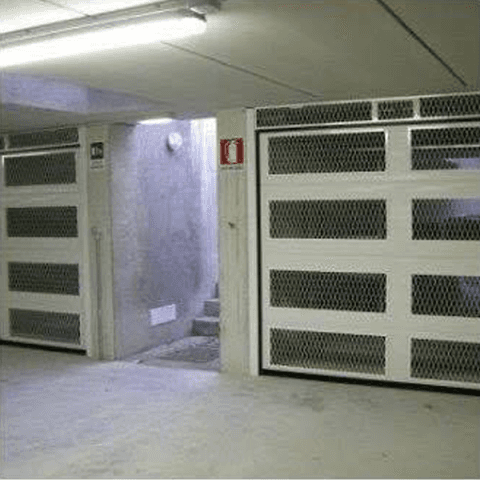 Un garage con una scala che conduce al seminterrato e una porta da garage bianca.