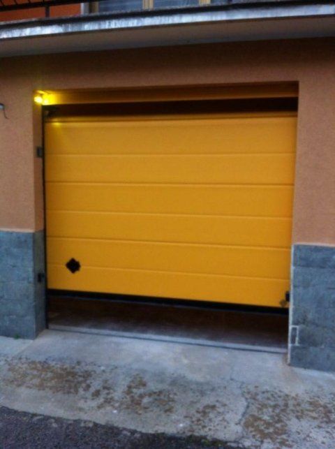 Una porta da garage gialla è aperta davanti a un edificio
