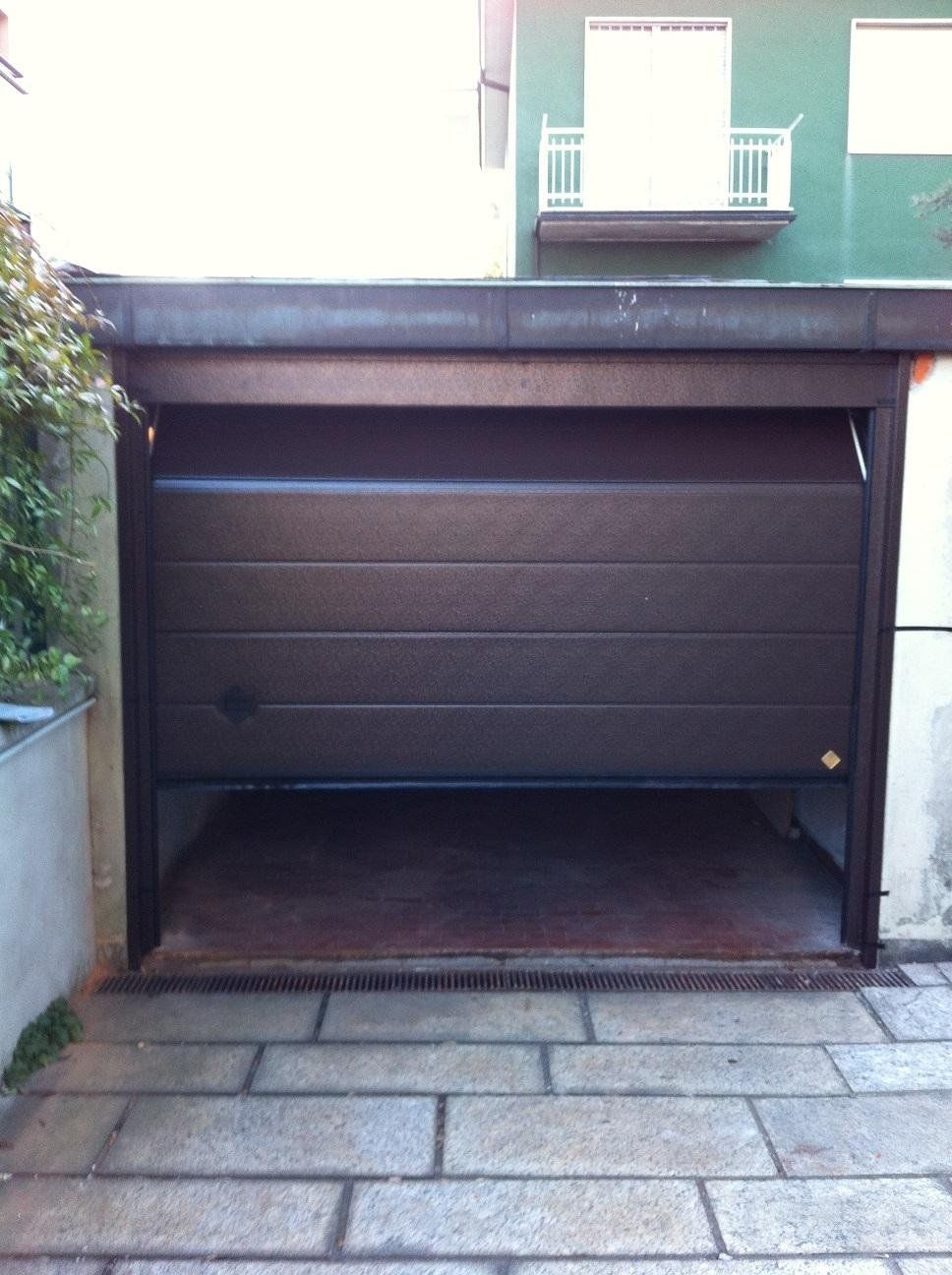 Una porta di garage è aperta davanti a un edificio verde.