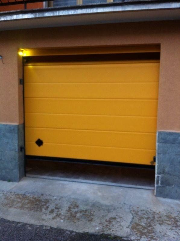 Una porta di garage gialla è aperta davanti a un edificio