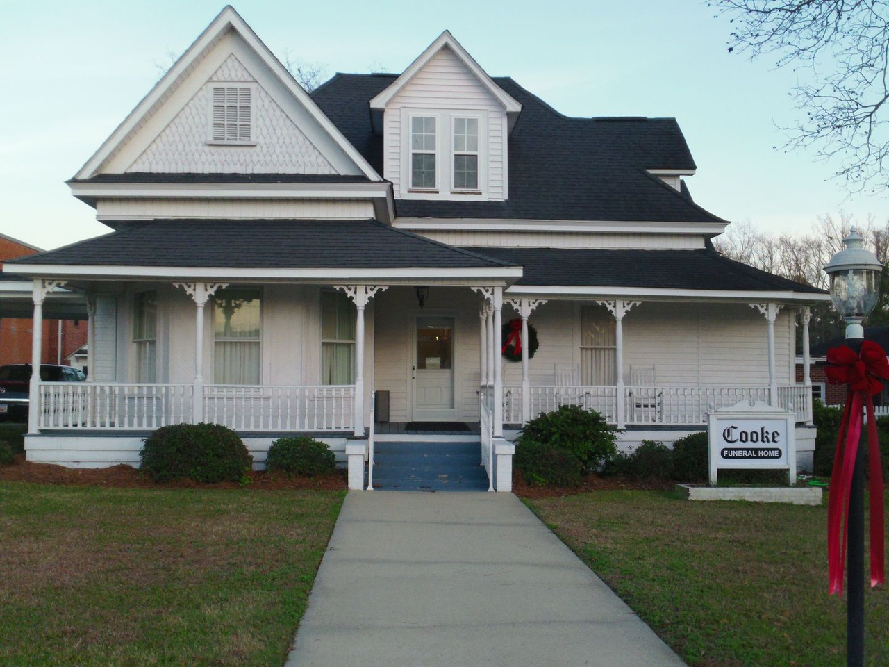 The front door of a house with a porch and plants in front of it.