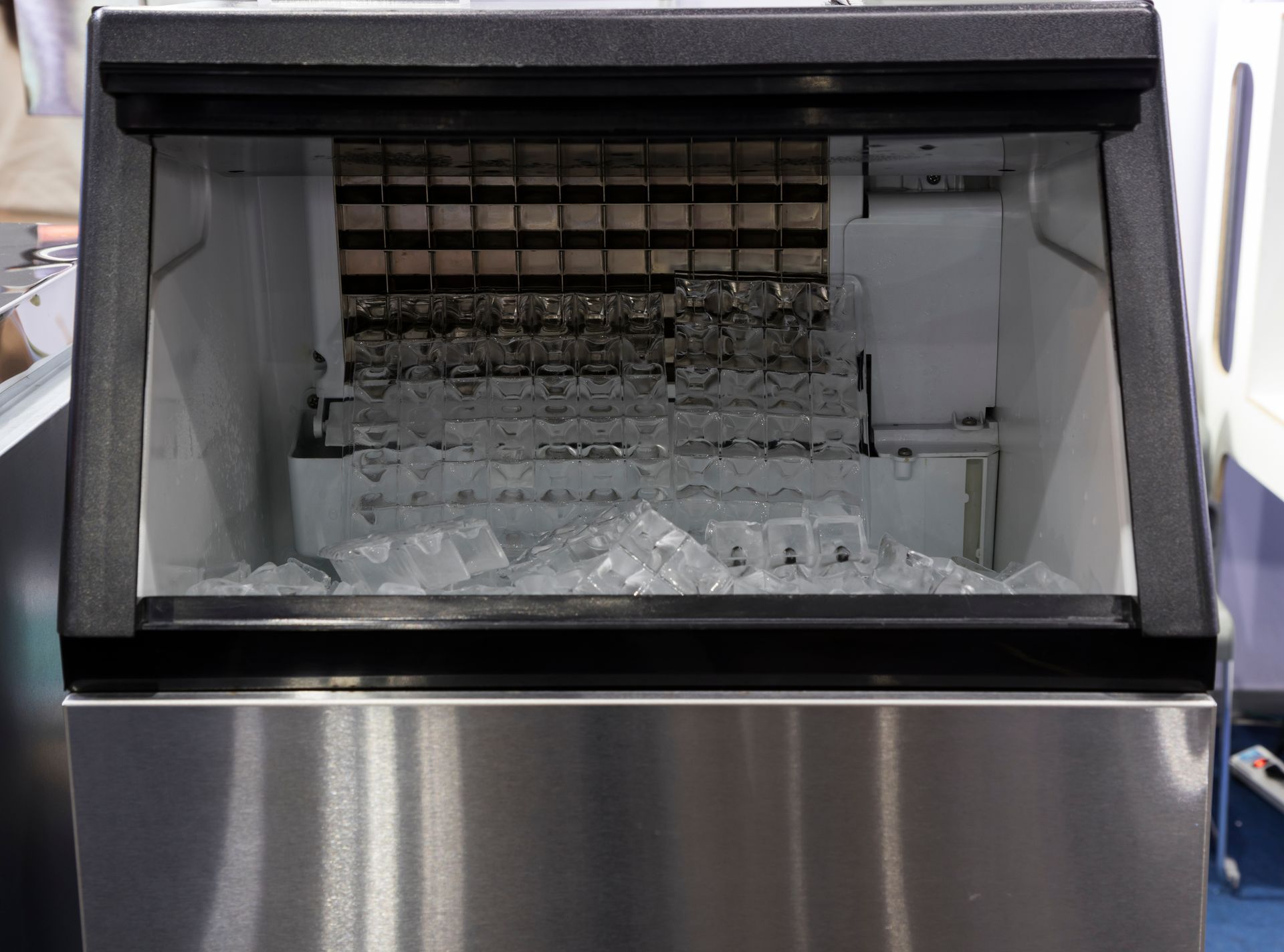 Stainless steel ice machine dispensing cube ice into its storage bin.