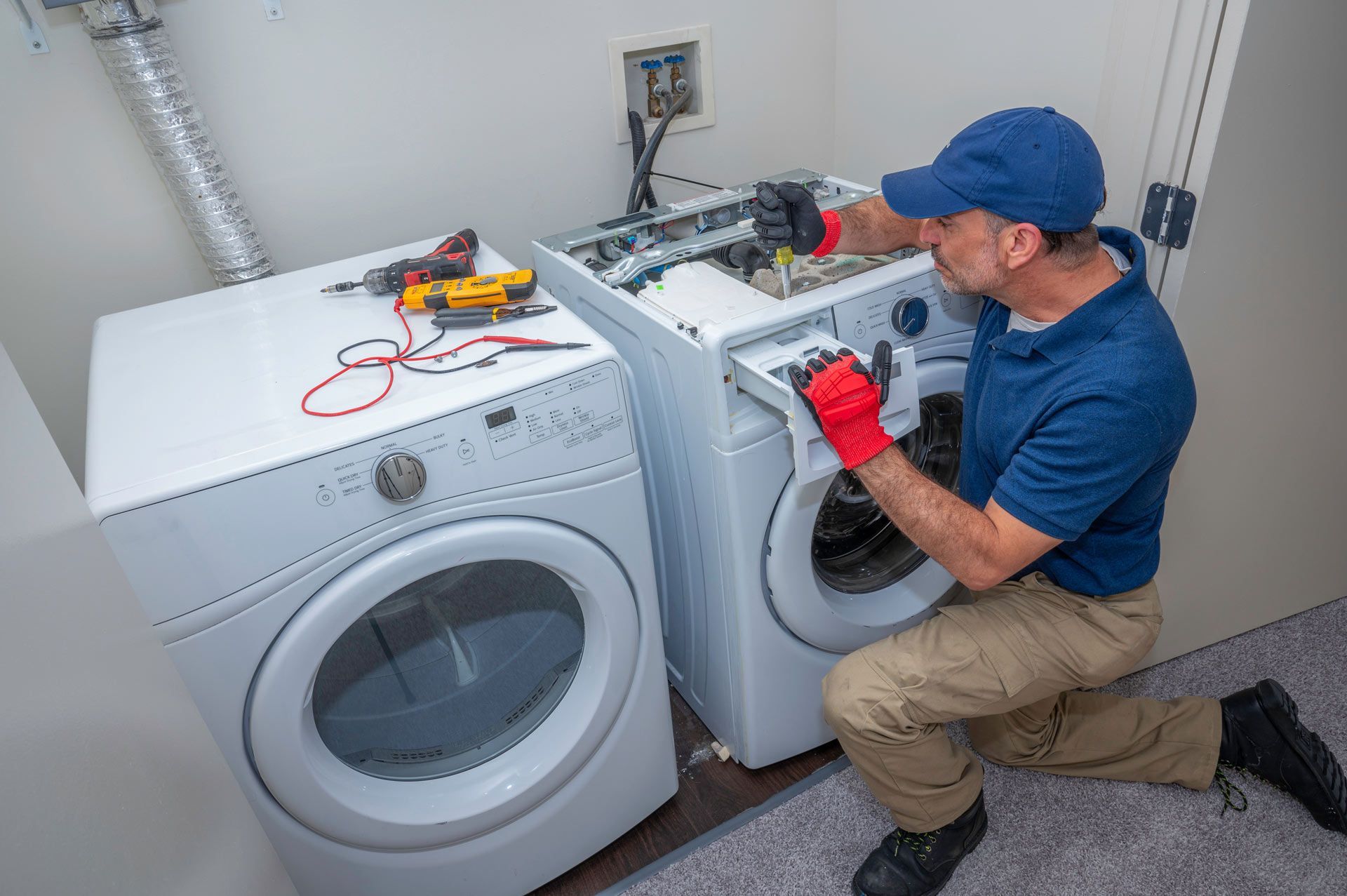 Technician repairing a washing machine with tools in a laundry room setting. Technician repairing a washing machine with tools in a laundry room setting.